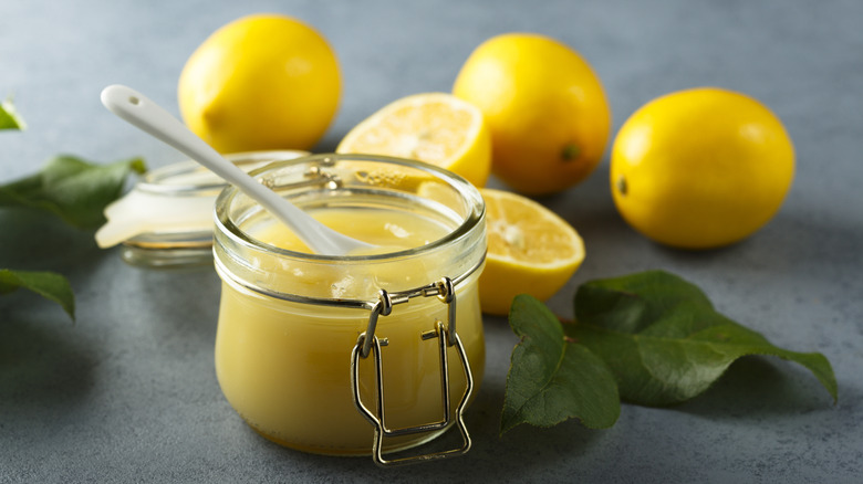 jar of lemon curd in front of several fresh lemons