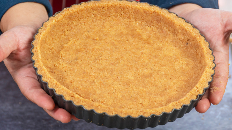 A person holding up a perfectly baked golden pie crust