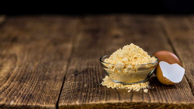 A small bowl of powdered eggs next to an eggshell