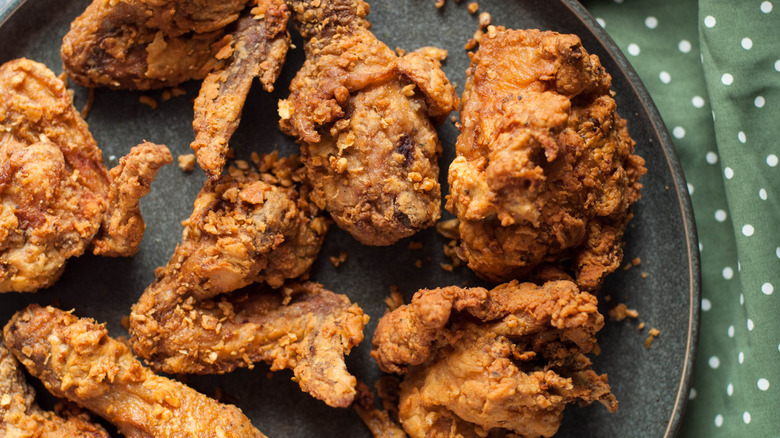 Fried chicken on a round black plate on top of a green polka-dot tablecloth