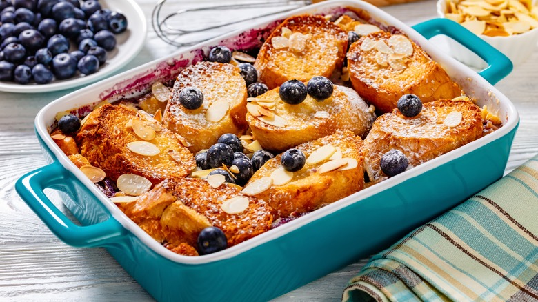 French toast bake with fresh blueberries and sliced almonds in a blue and white serving dish.