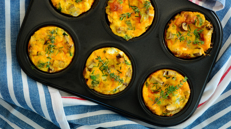 egg muffins in a muffin pan with mushrooms, fresh herbs