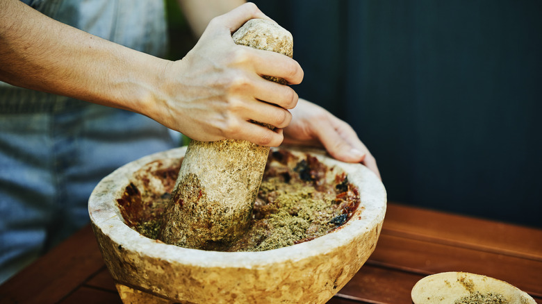 Grinding salsa in an earthen stone mortar and pestle