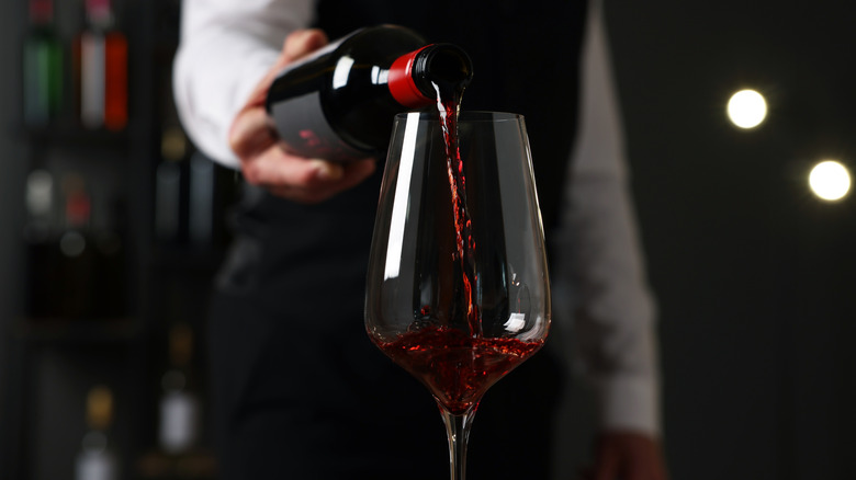 Sommelier pouring red wine into glass