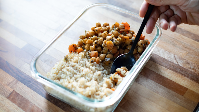 Hand spooning rice and chickpeas from container