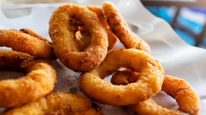 a pile of freshly fried onion rings on parchment paper