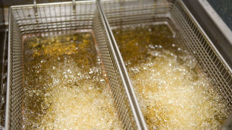 a close-up of two baskets submerged in deep fryer