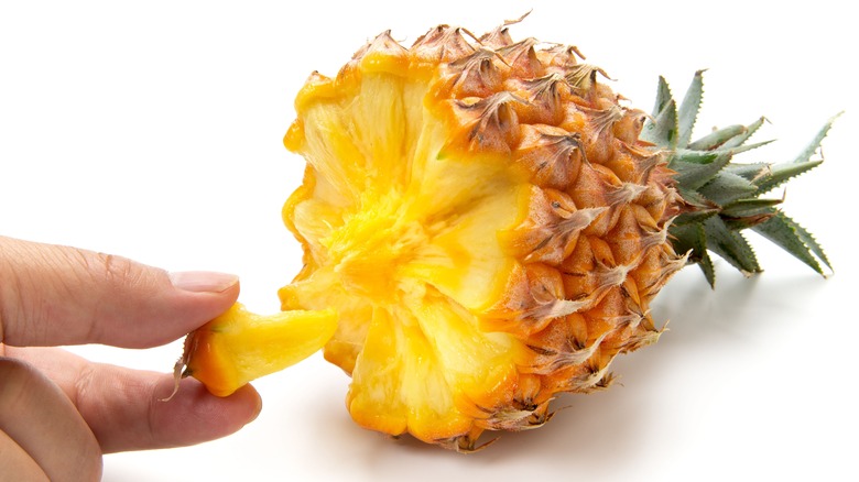 Person holding a pineapple piece