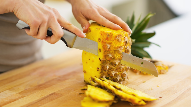 Person cutting pineapple with knife