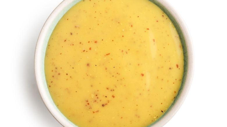 Closeup of a container of Raising Cane honey mustard sauce