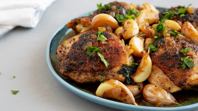 Cooked chicken, garlic, and parsley on a blue plate