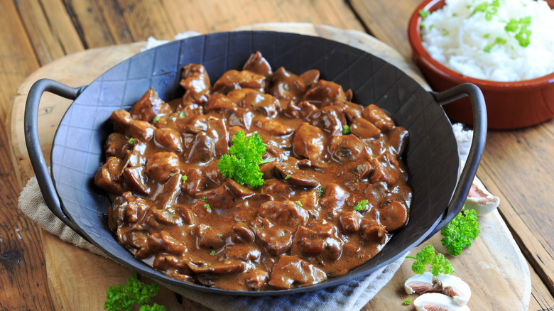 Beef stroganoff near a bowl of rice