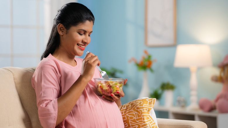 A pregnant woman eating fruit.