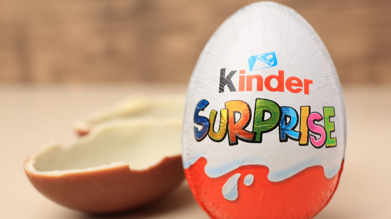 Wrapped Kinder Surprise egg with an open half Kinder Surprise egg behind it.