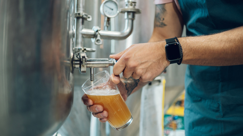 Brewer filling glass from beer tank