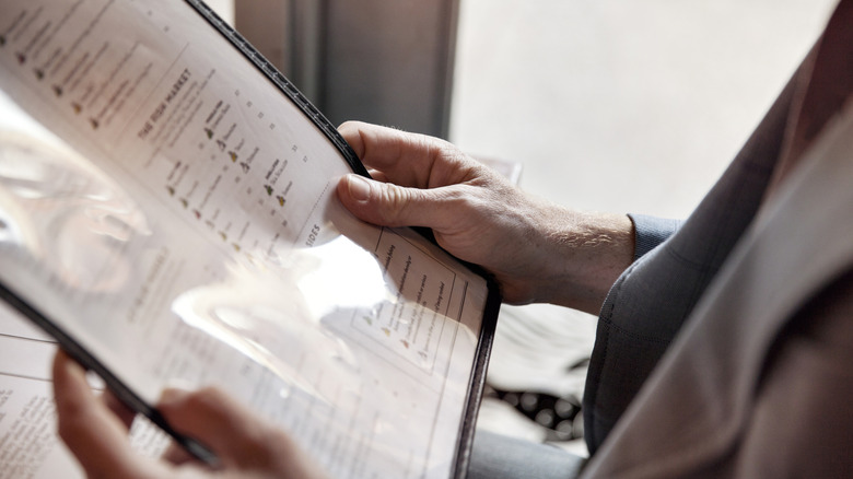 A person holding a restaurant menu.