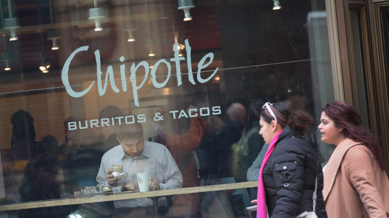 People walk past Chipotle window