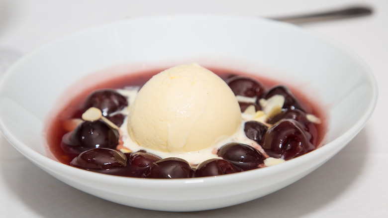 White bowl with cherries jubilee and vanilla ice cream