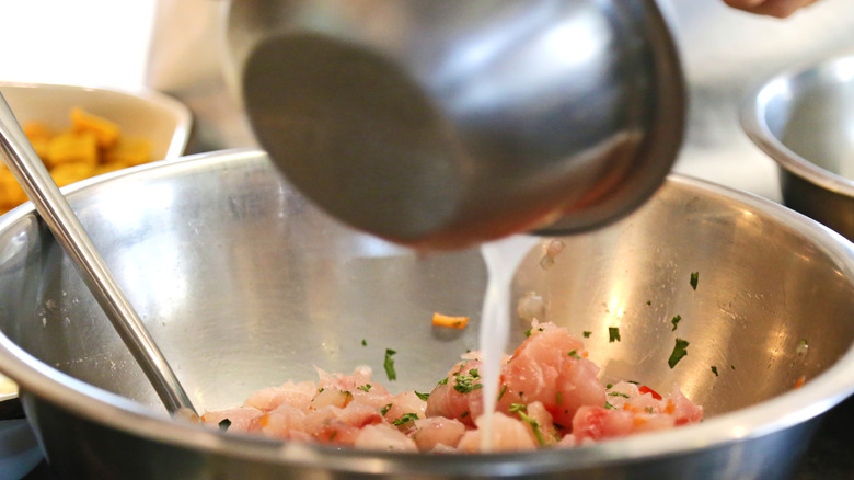 Lime juice being poured into a bowl of raw seafood