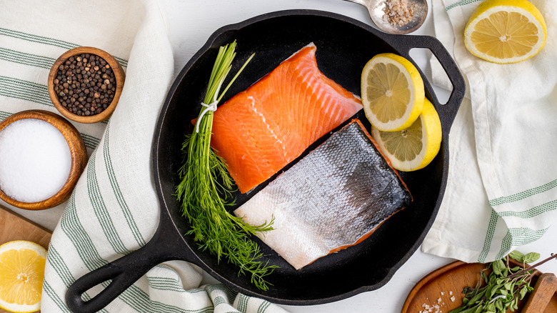 Coho salmon and lemons in a black pan.