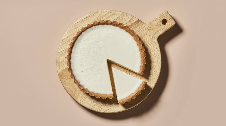 Vanilla cheesecake sitting on a round cutting board