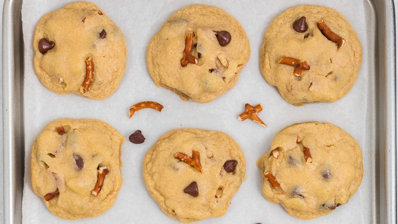 Six chocolate chip pretzel cookies on a silver tray.