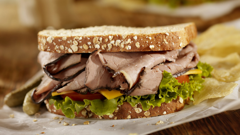 A roast beef sandwich rests on a plate