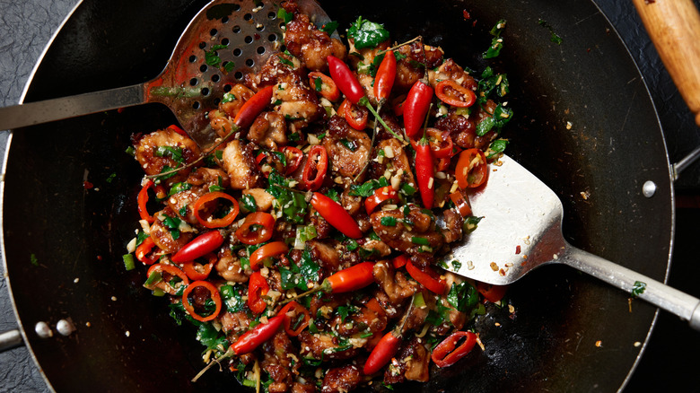 Meat and sichuan peppers frying in a large wok