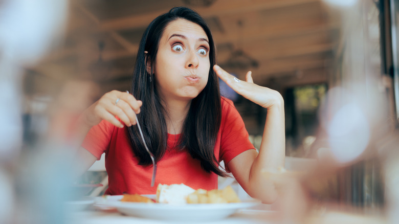 A person wearing a red top and eating spicy food