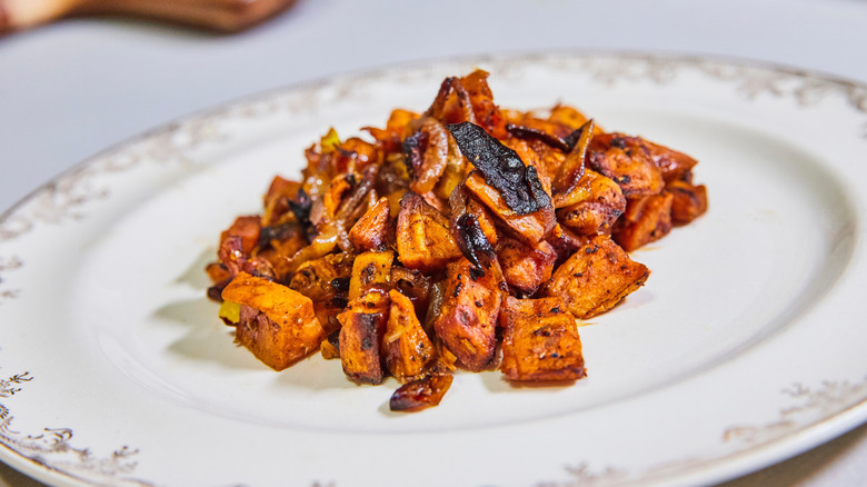 roasted sweet potatoes caramelized and chopped on ornate white plate