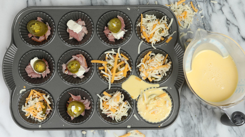 Bits of jalapeño, cheese, meat and egg mixture in a baking tray