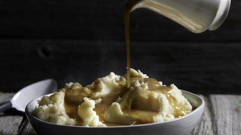 Bowl of mashed potatoes with gravy being poured over them