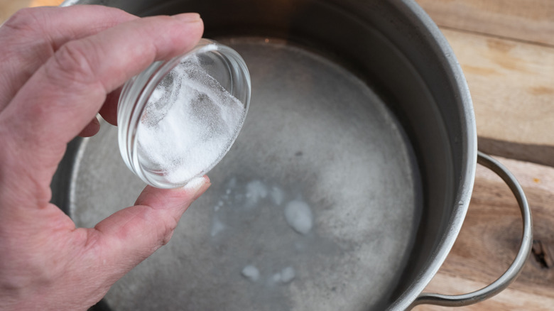 Adding baking soda to a pot of water