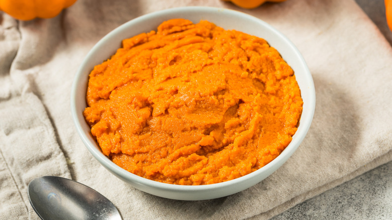 Pumpkin purée in a white bowl on a kitchen towel