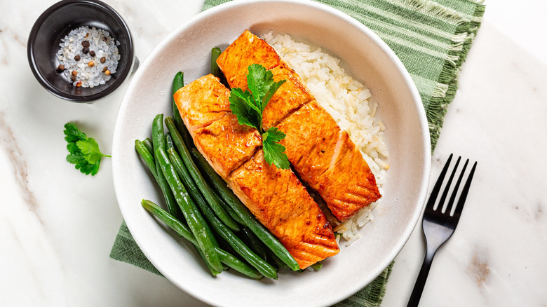 Glazed roasted salmon with long rice and green beans on white plate