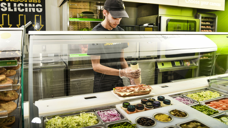 Subway employee assembling a sandwich in the store