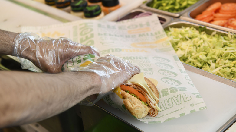 A Subway employee wrapping a sandwich