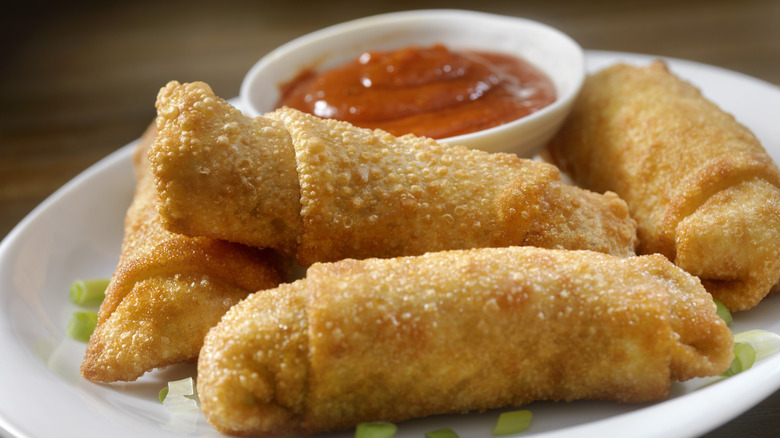 egg rolls on white plate with red sauce