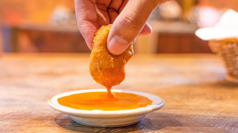 hand dipping nugget in sauce