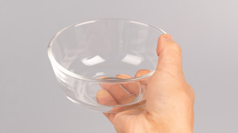 A hand holding an empty glass bowl.