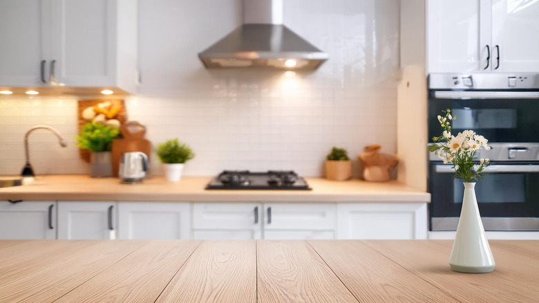 Spotless kitchen with wood counters and a vase of fresh flowers in a white vase.