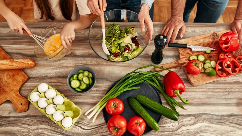 the hands of a family preparing components of a salad