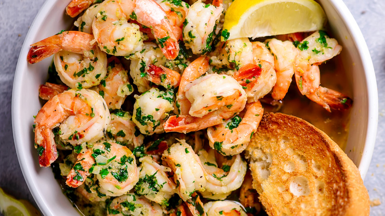 Garlic shrimp, toast, and a lemon slice in a bowl of broth