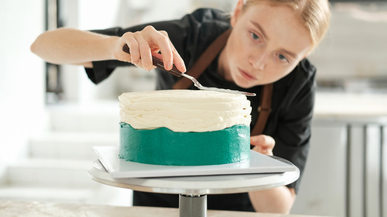 woman frosting a cake on cake turntable