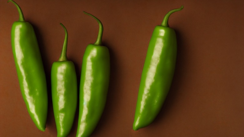 Whole green jalapeños on a brown surface