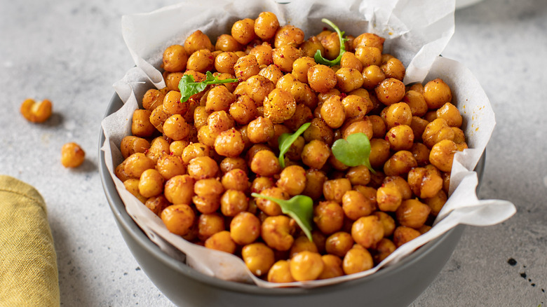 Fried chickpeas in a paper lined grey bowl  on a light grey surface.