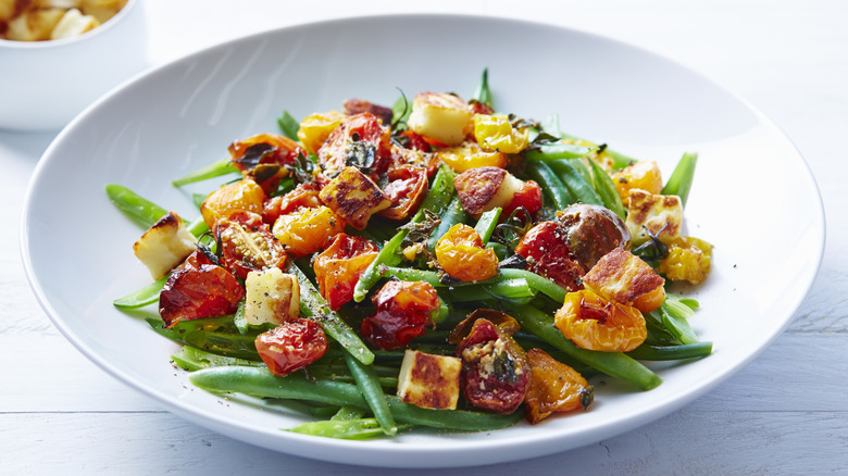 String bean salad with air fried chickpeas on a white plate.