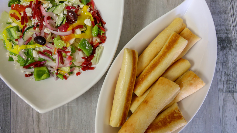 A bowl of Olive Garden breadsticks and a bowl of salad