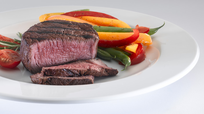 A steak on a plate with sliced bell peppers