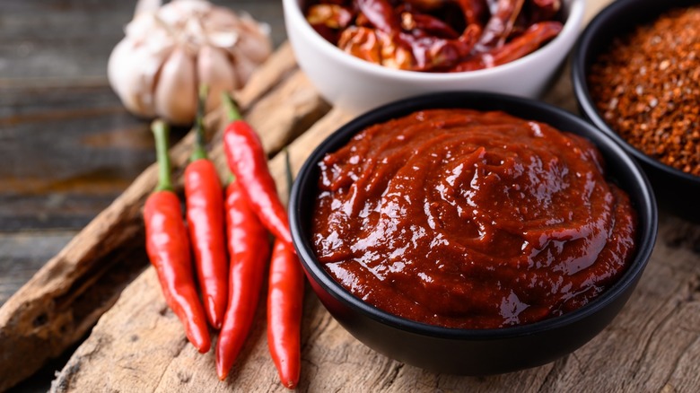 Korean Gochujang chili paste in a bowl with whole and ground chilis